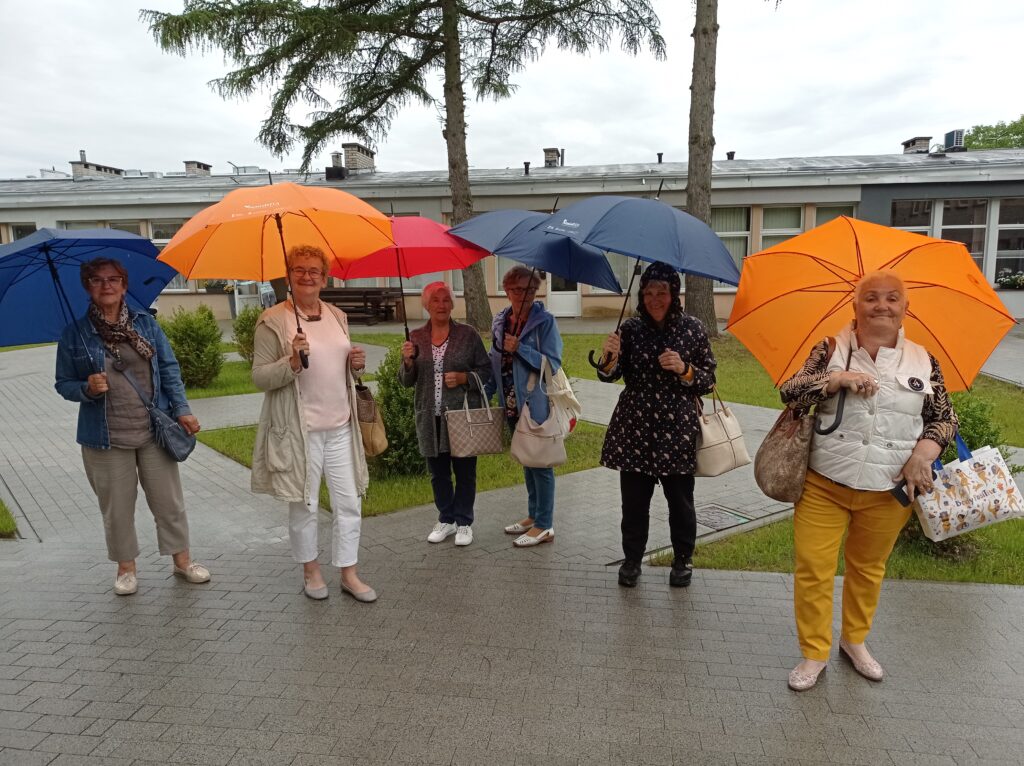 Seniorzy z parasolami w deszczu